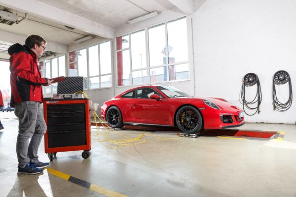 PKW-Messung – 600 x 400 Roter Porsche 911 auf dem Prüfstand, Sachverständiger mit Messtechnik daneben